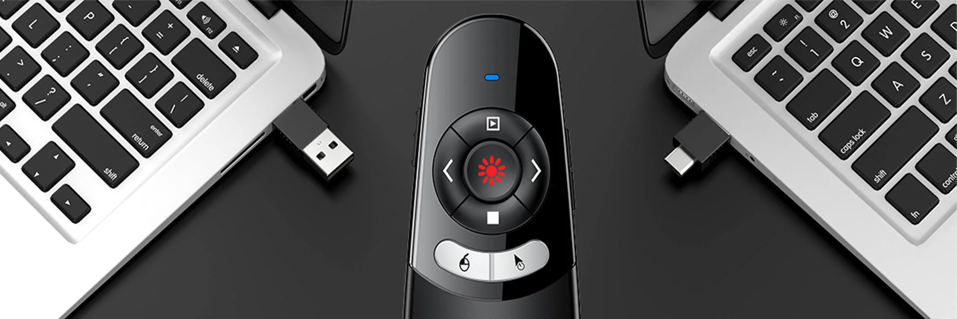 An oval presentation remote on a dark desk between two laptops, with its USB-A and USB-C receiver ends showing